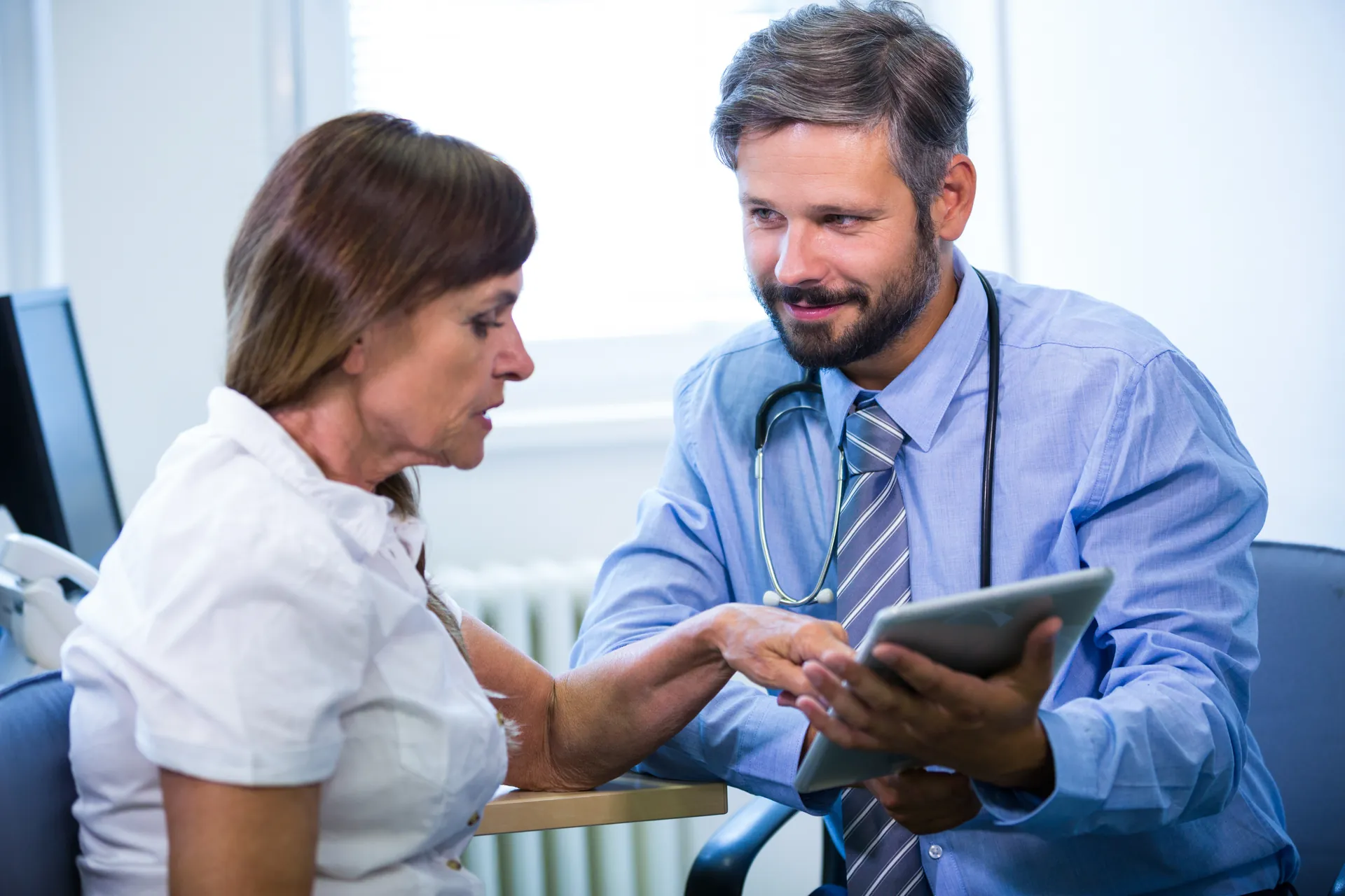Du rendez-vous à la consultation Médecin qui échange avec un patient autour d’une tablette